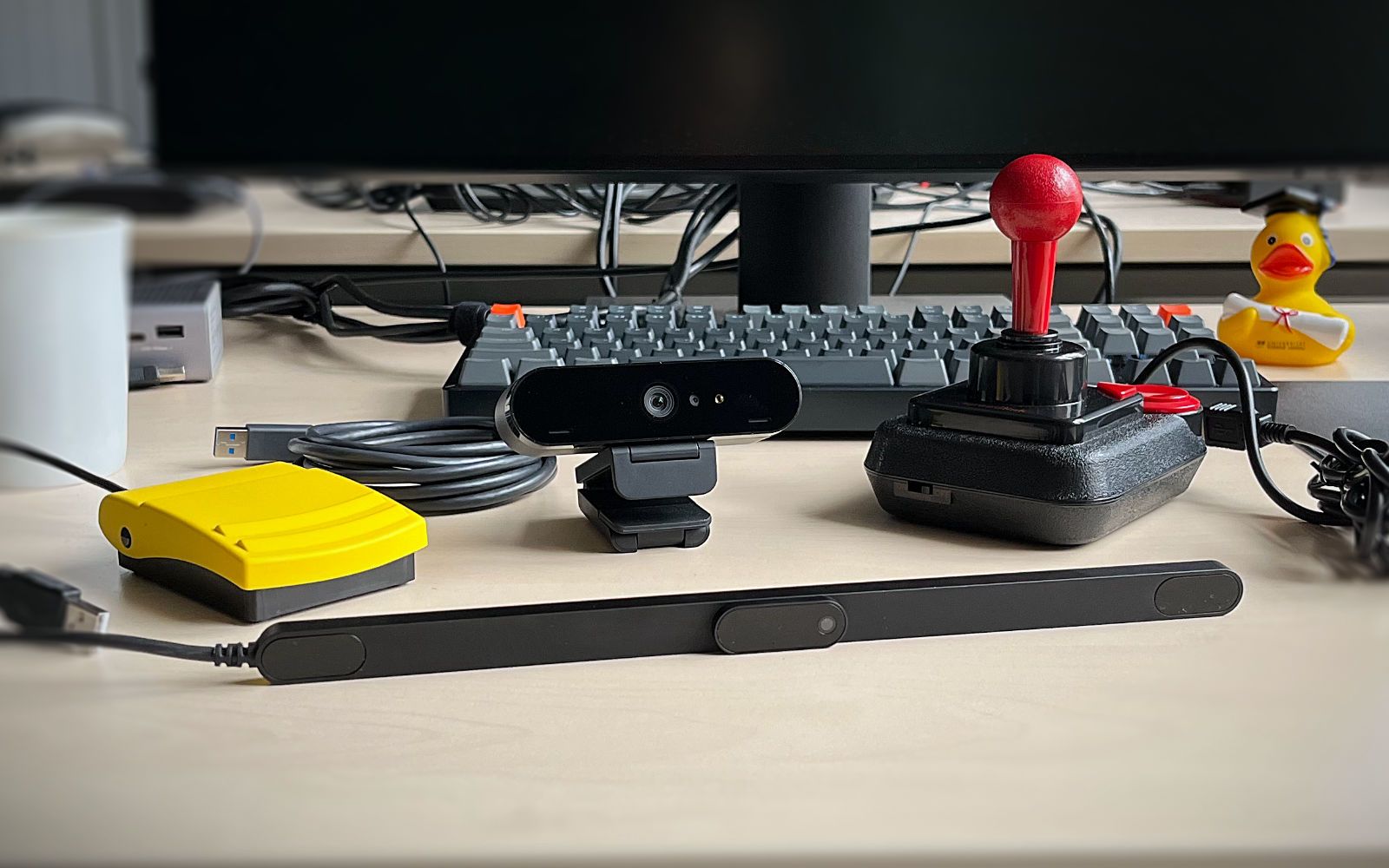 Multiple input devices on a desk, i.e., a foot pedal, a webcam, a joystick, and an eyetracker.
