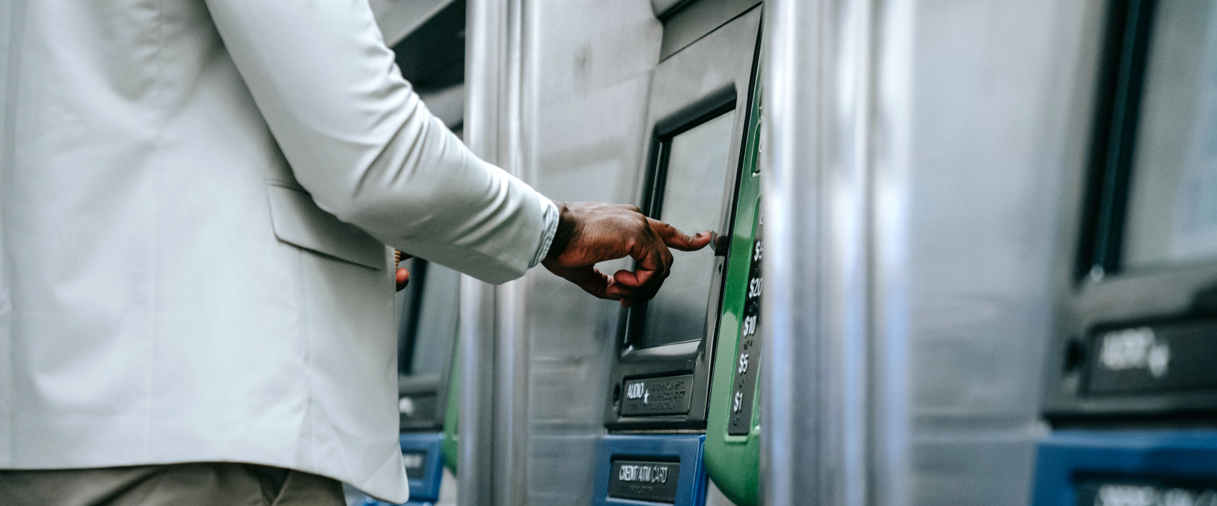 Ein Mann drückt auf den Bildschirm eines Ticketautomaten mit seinem Finger.